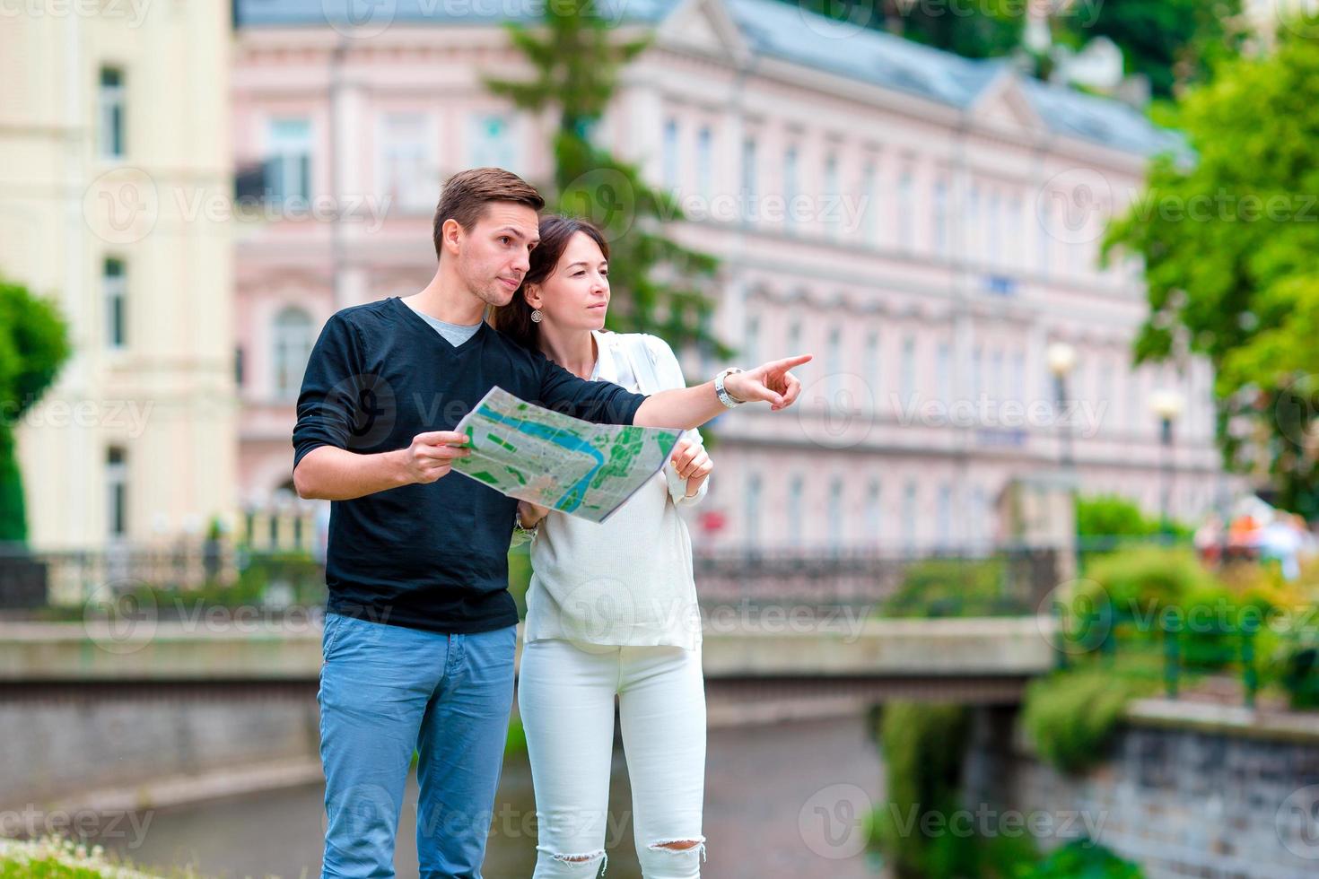 Young tourist couple traveling on holidays in Europe. Caucasian family with city map in search of attractions photo
