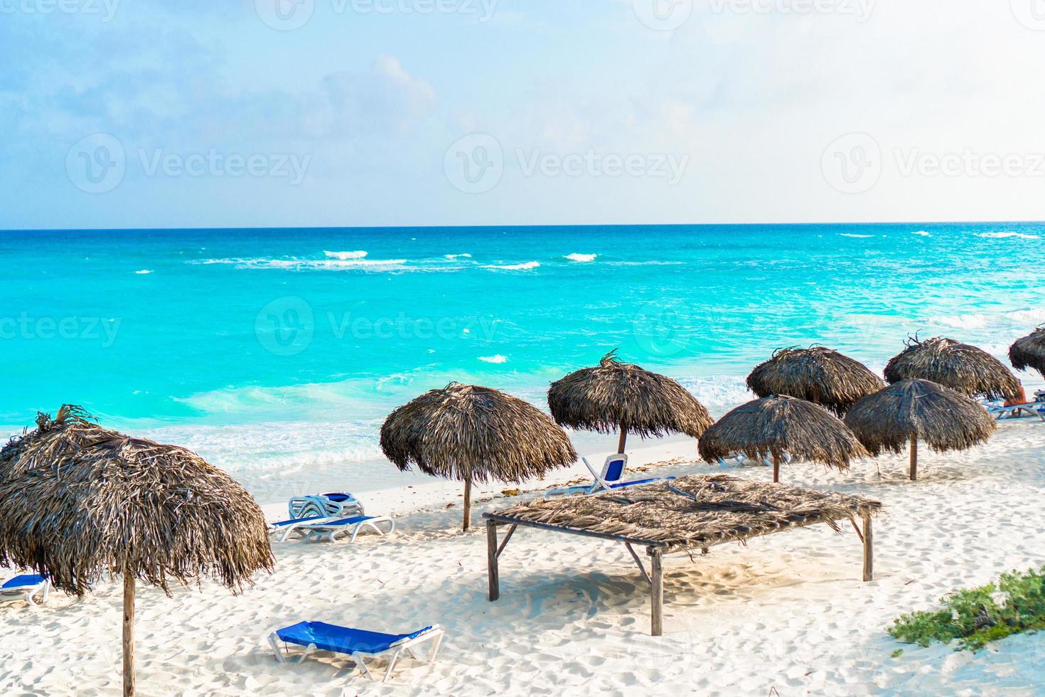 Beach sunbeds and umbrellas on white beach in caribbean island photo