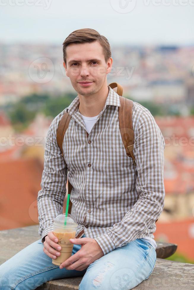 Happy young urban man drinking coffee background european city outdoors photo