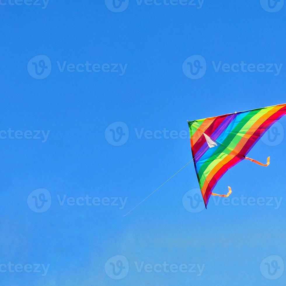 Rainbow kite flying in blue sky with clouds photo