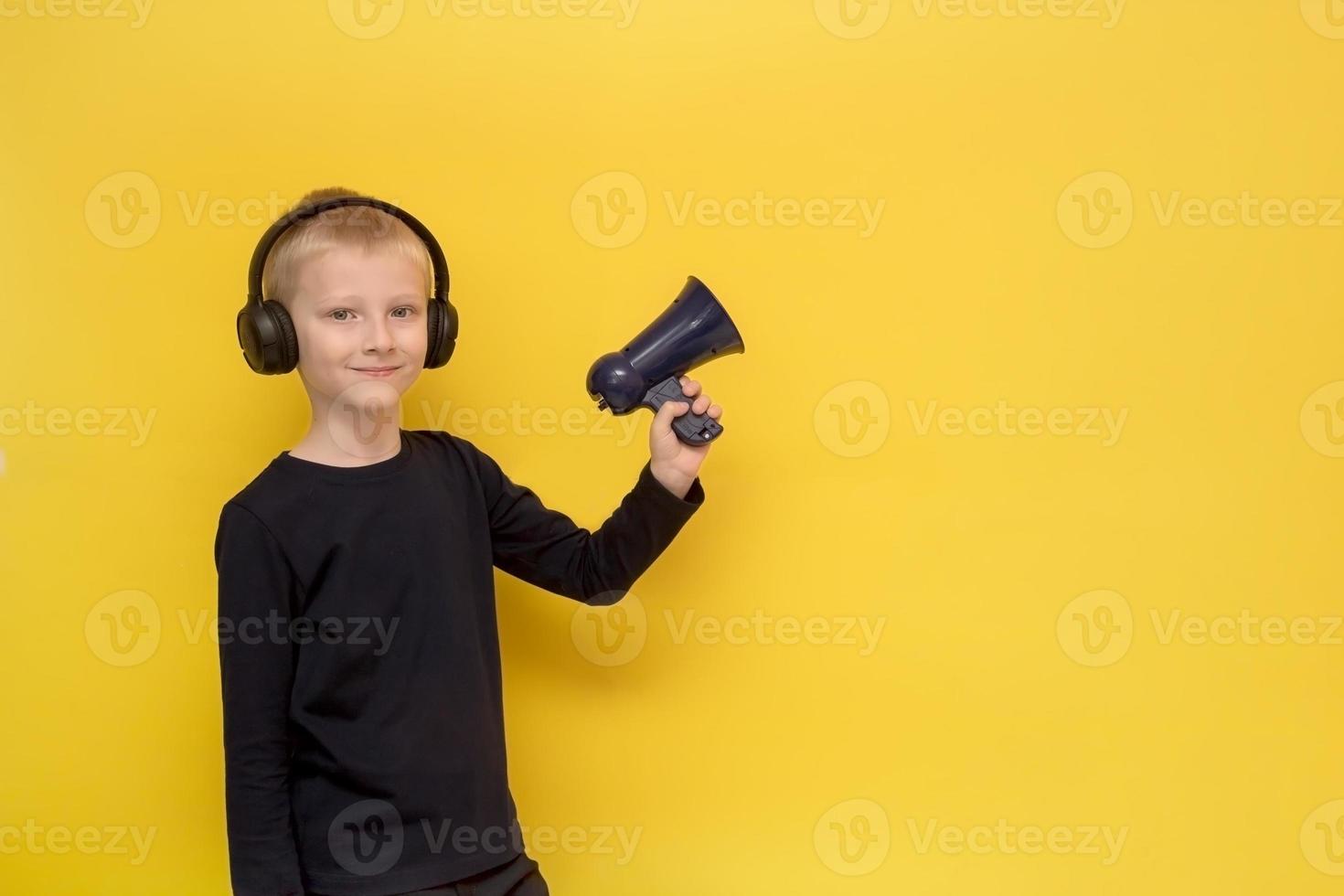 chico con auriculares y con un megáfono en la mano con un fondo amarillo foto