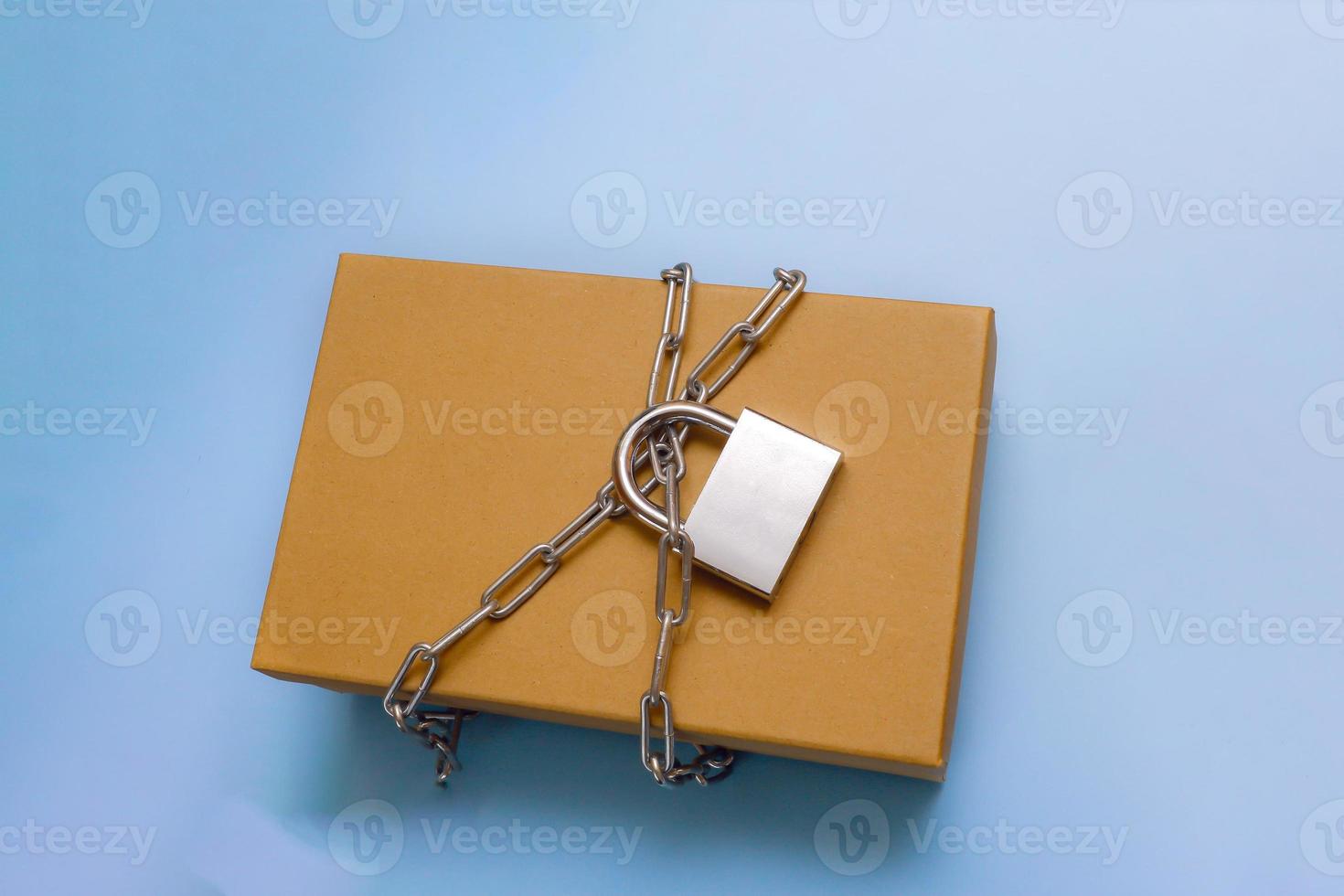 box in chains and under lock and key on a blue background photo