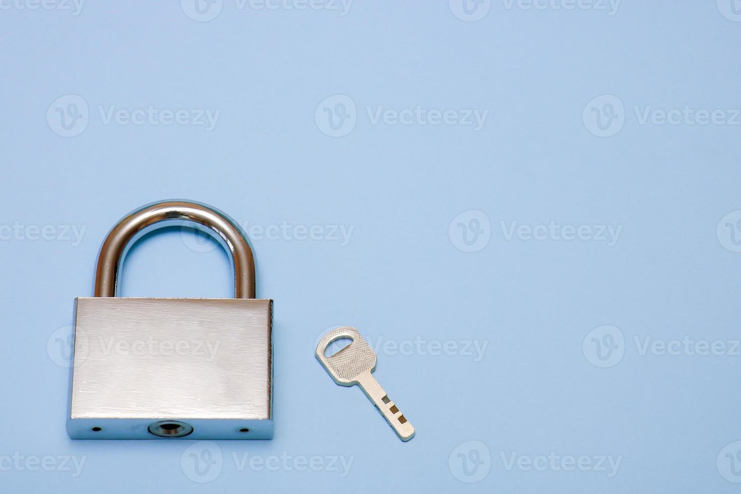 padlock and key on a blue background with copy space, security, reliability photo