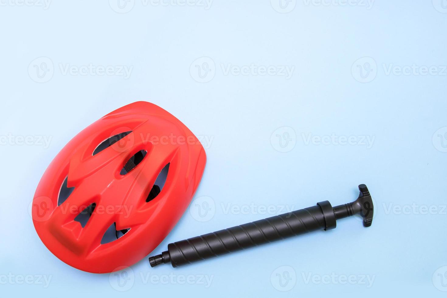 protective helmet for a bicycle and a pump on a blue background with copy space photo