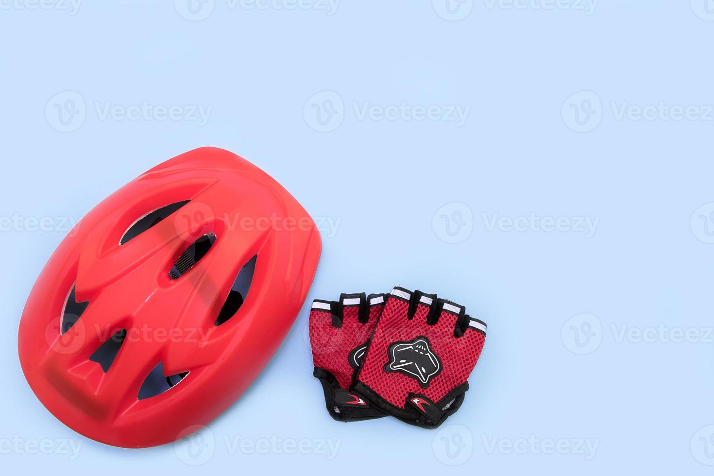 casco de bicicleta rojo y guantes de bicicleta sobre fondo azul con espacio de copia foto