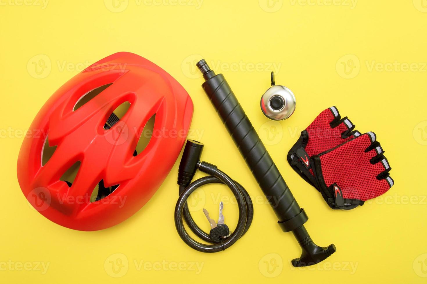 bicycle accessories - helmet, bell, lock with keys, gloves, pump on a yellow background photo