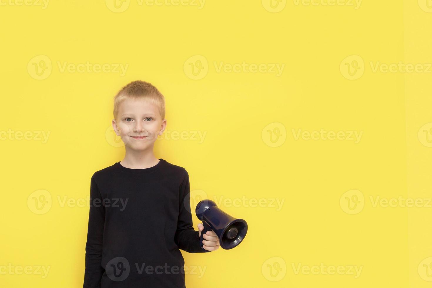 cute boy with a megaphone in his hand on a yellow background with copy space photo