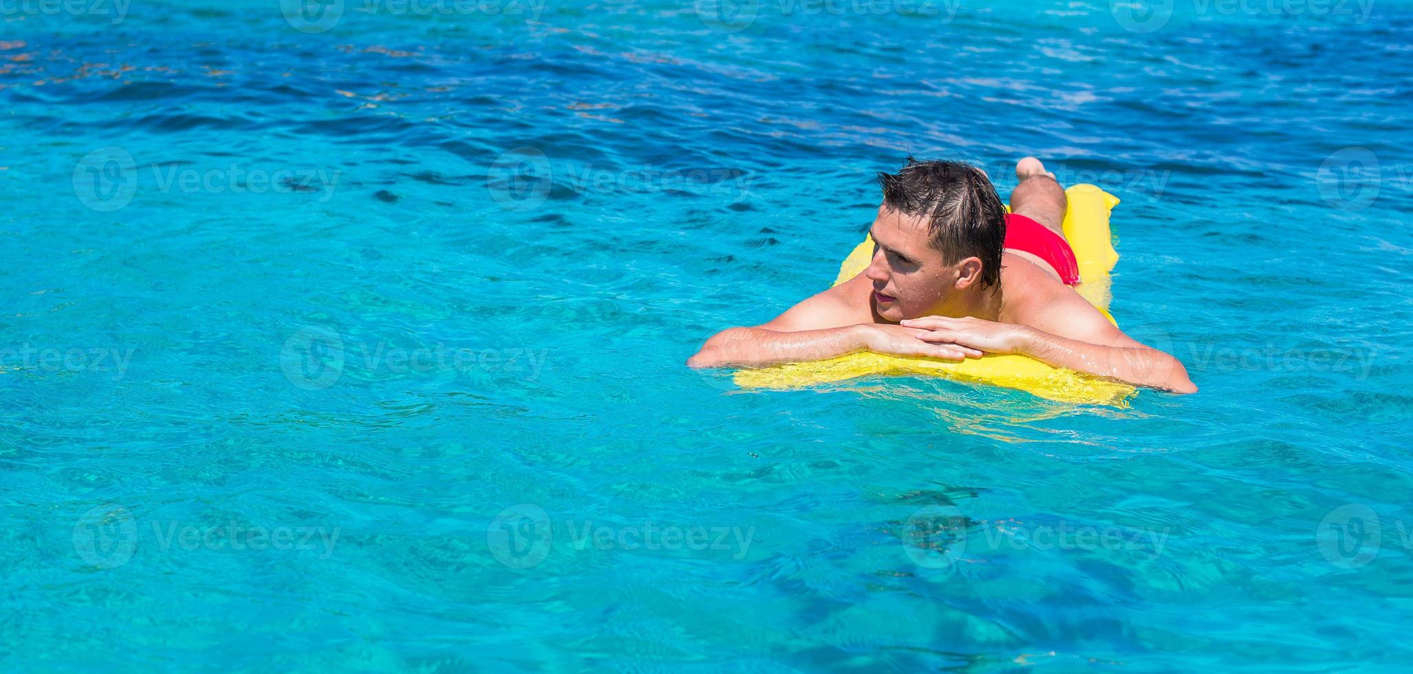 joven relajándose en un colchón inflable en el mar foto