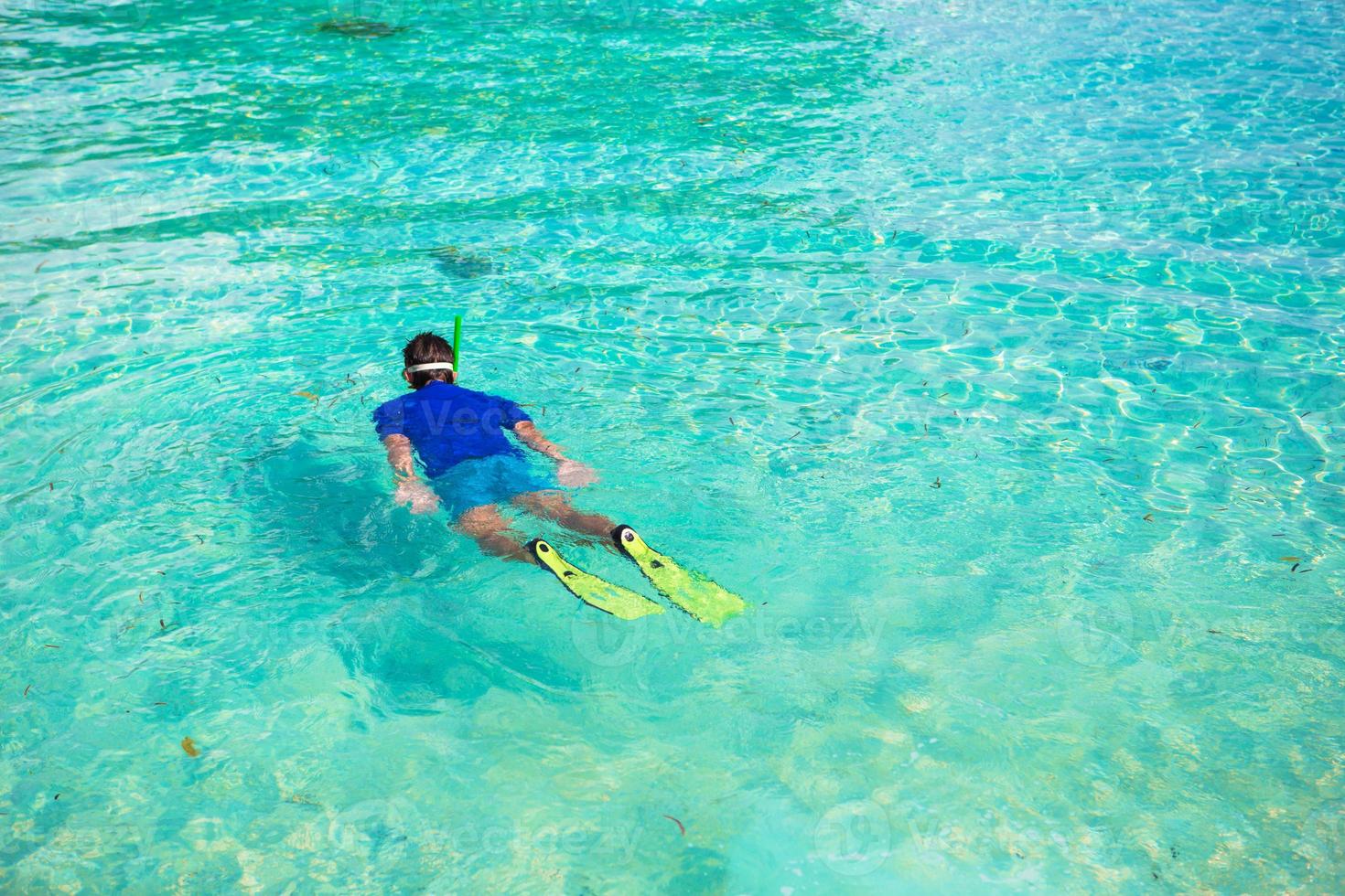 Young man snorkeling in clear tropical turquoise waters photo