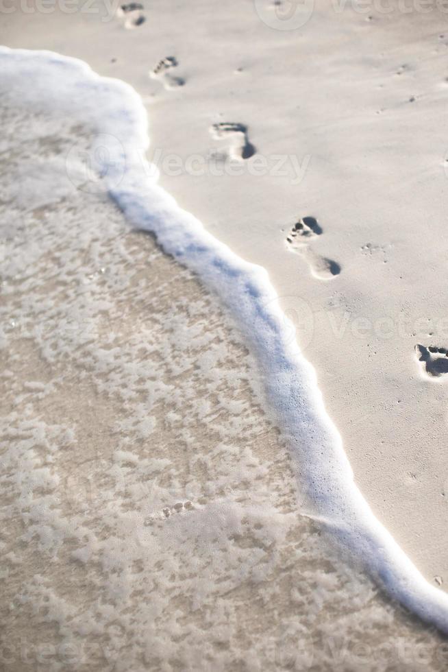 Human footprints on white sand of the Caribbean island photo