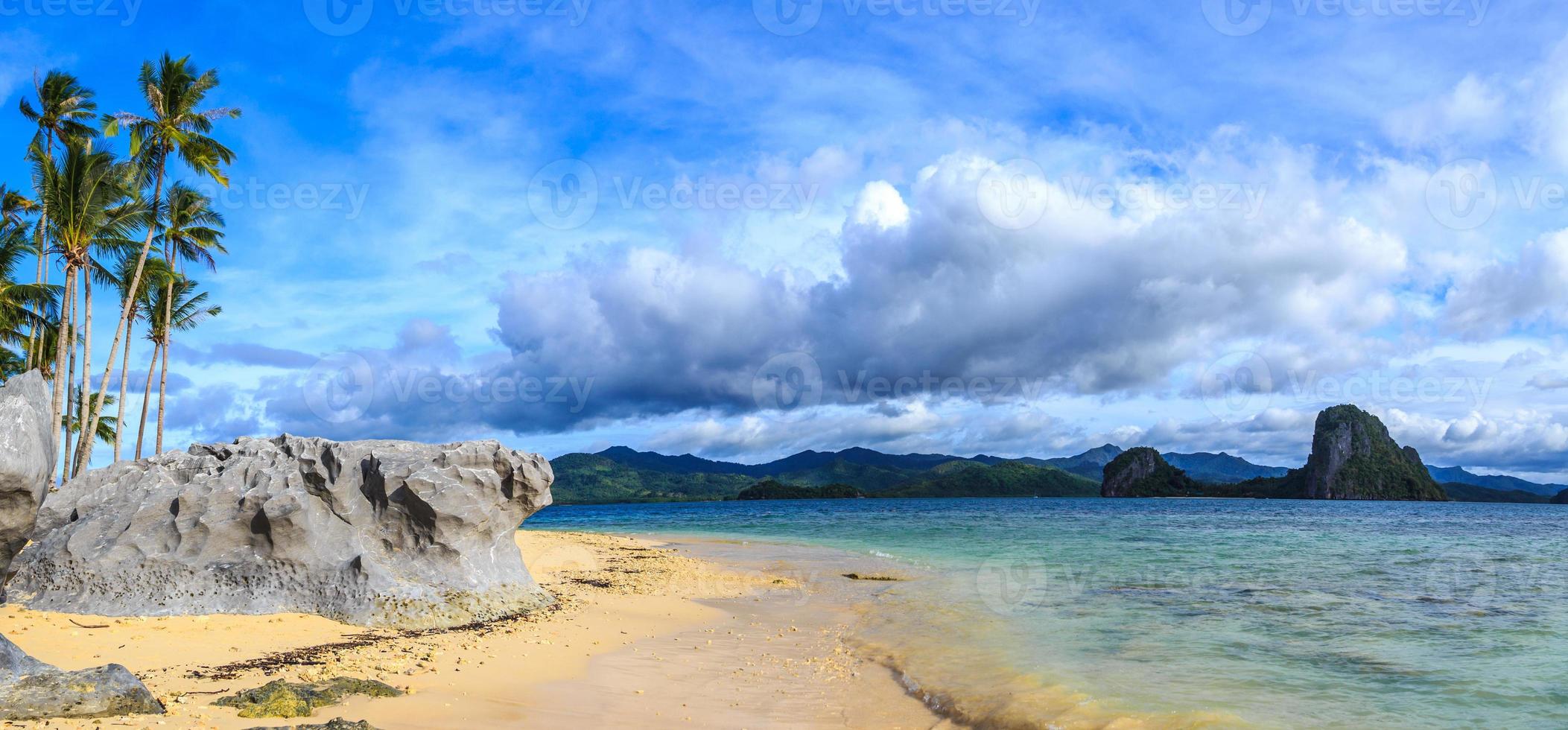panorama de playa tropical con cielo azul, nubes, rocas y palmeras, palawan, filipinas foto