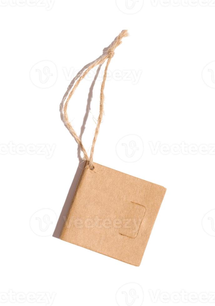 Brown paper square paper tag with a rope on a white isolated background photo