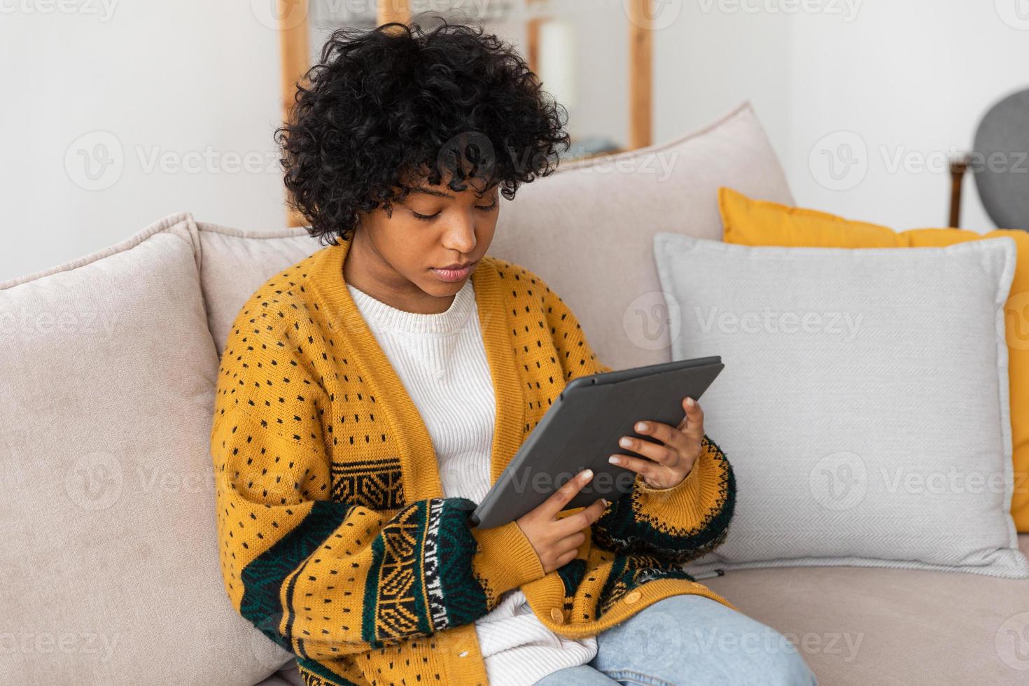 African american girl holding digital tablet touch screen typing scroll page at home. Woman with mobile tech device surfing internet using social media apps playing game. Study work shopping online. photo