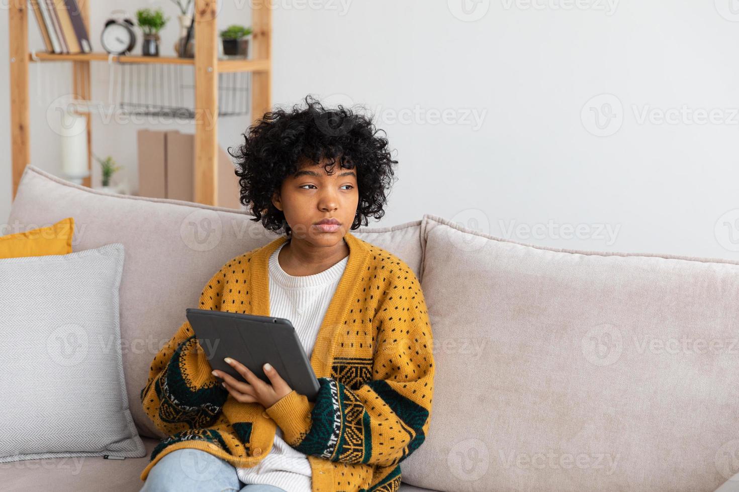 African american girl holding digital tablet touch screen typing scroll page at home. Woman with mobile tech device surfing internet using social media apps playing game. Study work shopping online. photo