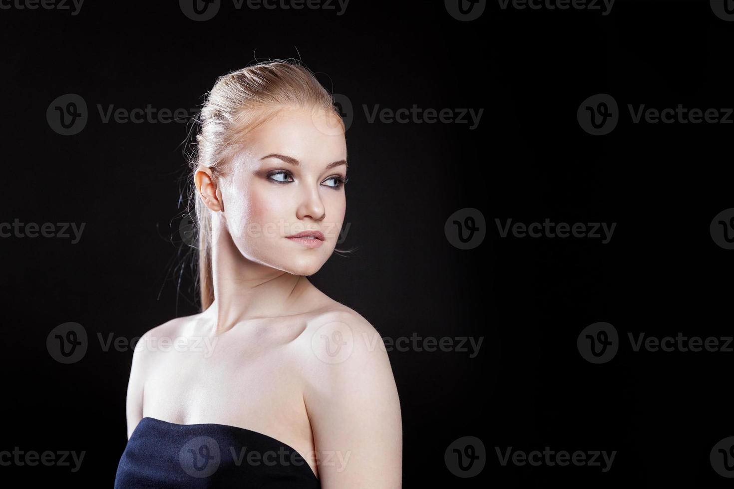 Beauty fashion model girl with long healthy smooth straight hair ponytail hairstyle on black background. Smiling pretty woman looking camera. Perfect Fresh Skin Portrait. Youth and Skin Care Concept. photo