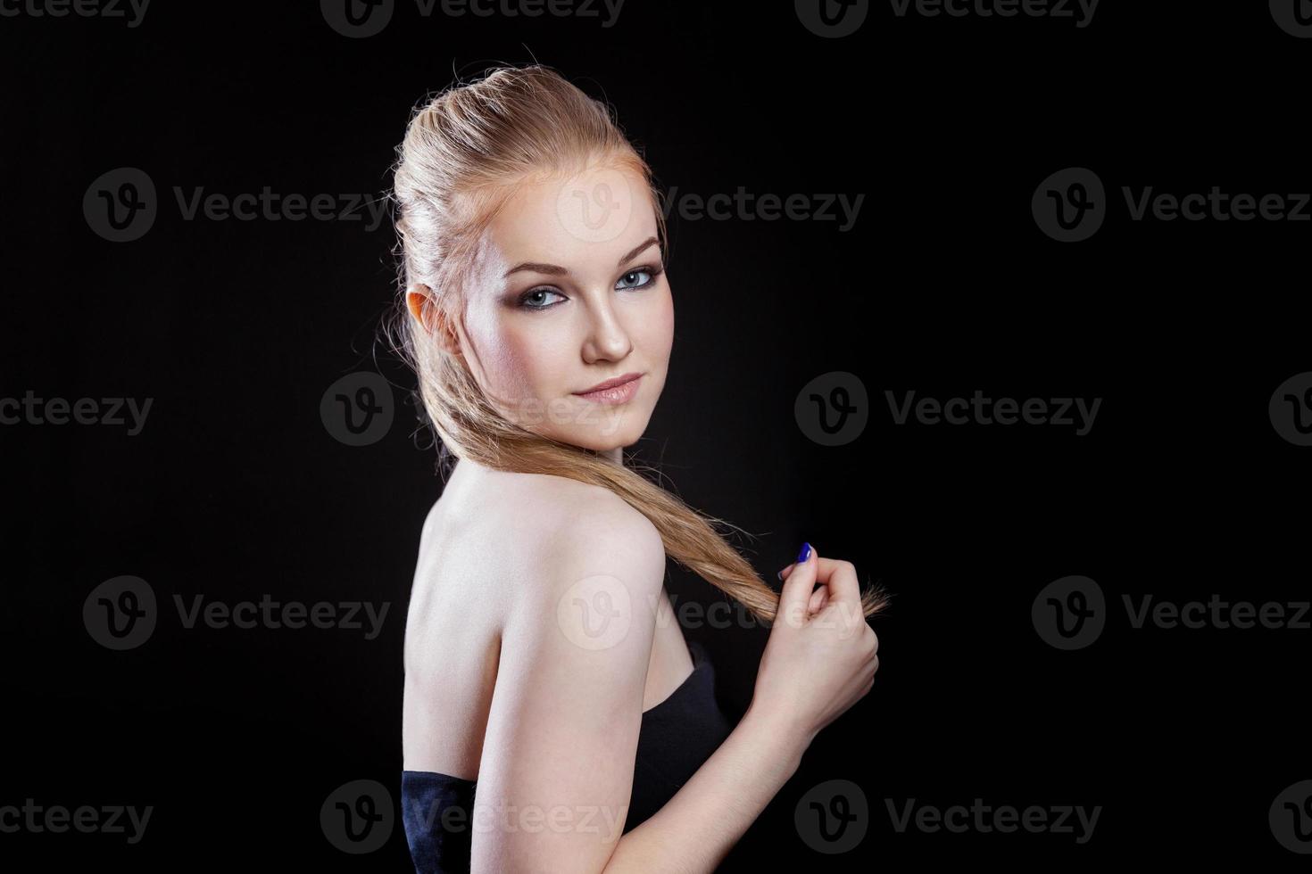 Beauty fashion model girl with long healthy smooth straight hair ponytail hairstyle on black background. Smiling pretty woman looking camera. Perfect Fresh Skin Portrait. Youth and Skin Care Concept. photo