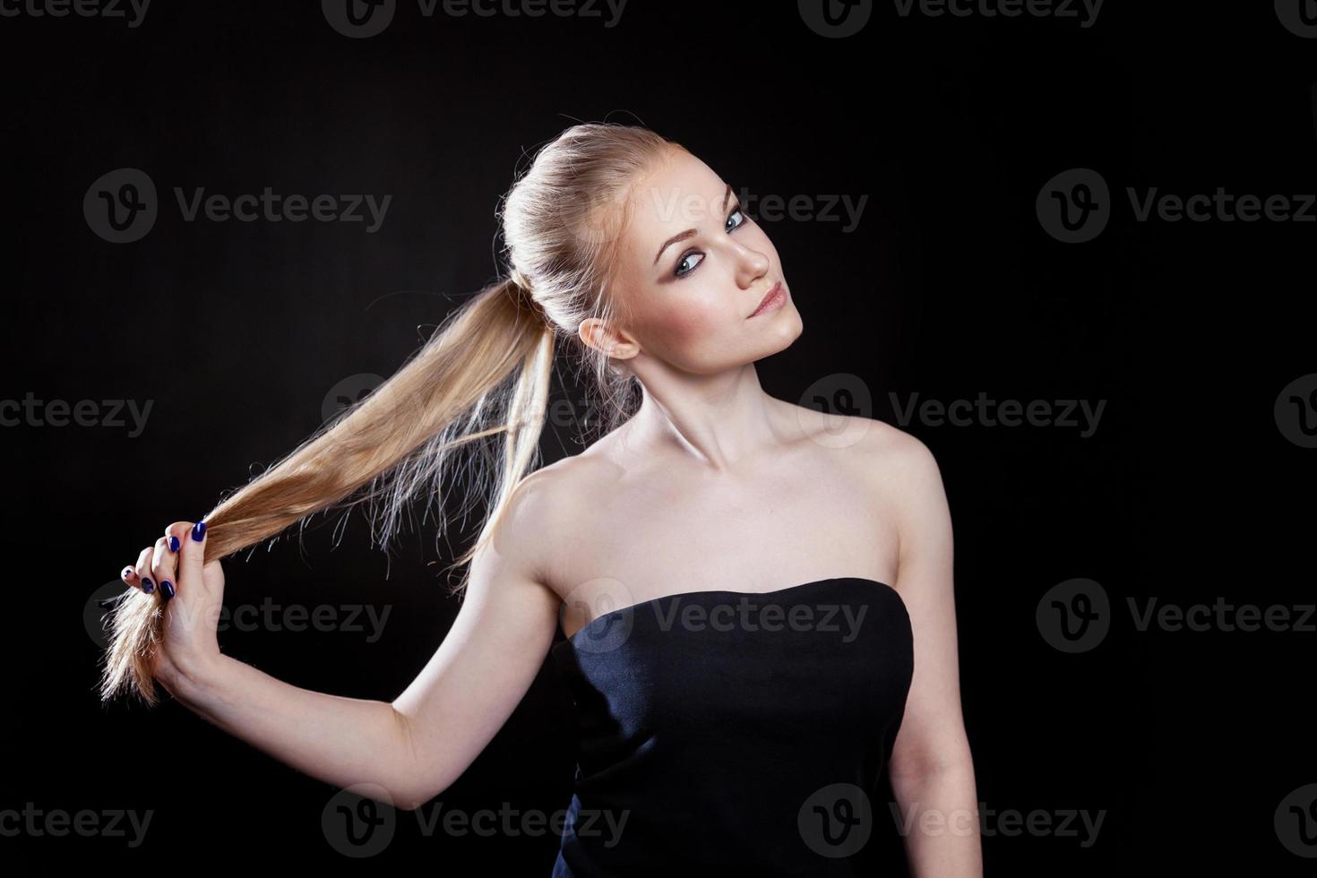 chica modelo de moda de belleza con peinado de cola de caballo de pelo recto largo y saludable sobre fondo negro. mujer bonita sonriente mirando la cámara. perfecto retrato de piel fresca. concepto de juventud y cuidado de la piel. foto