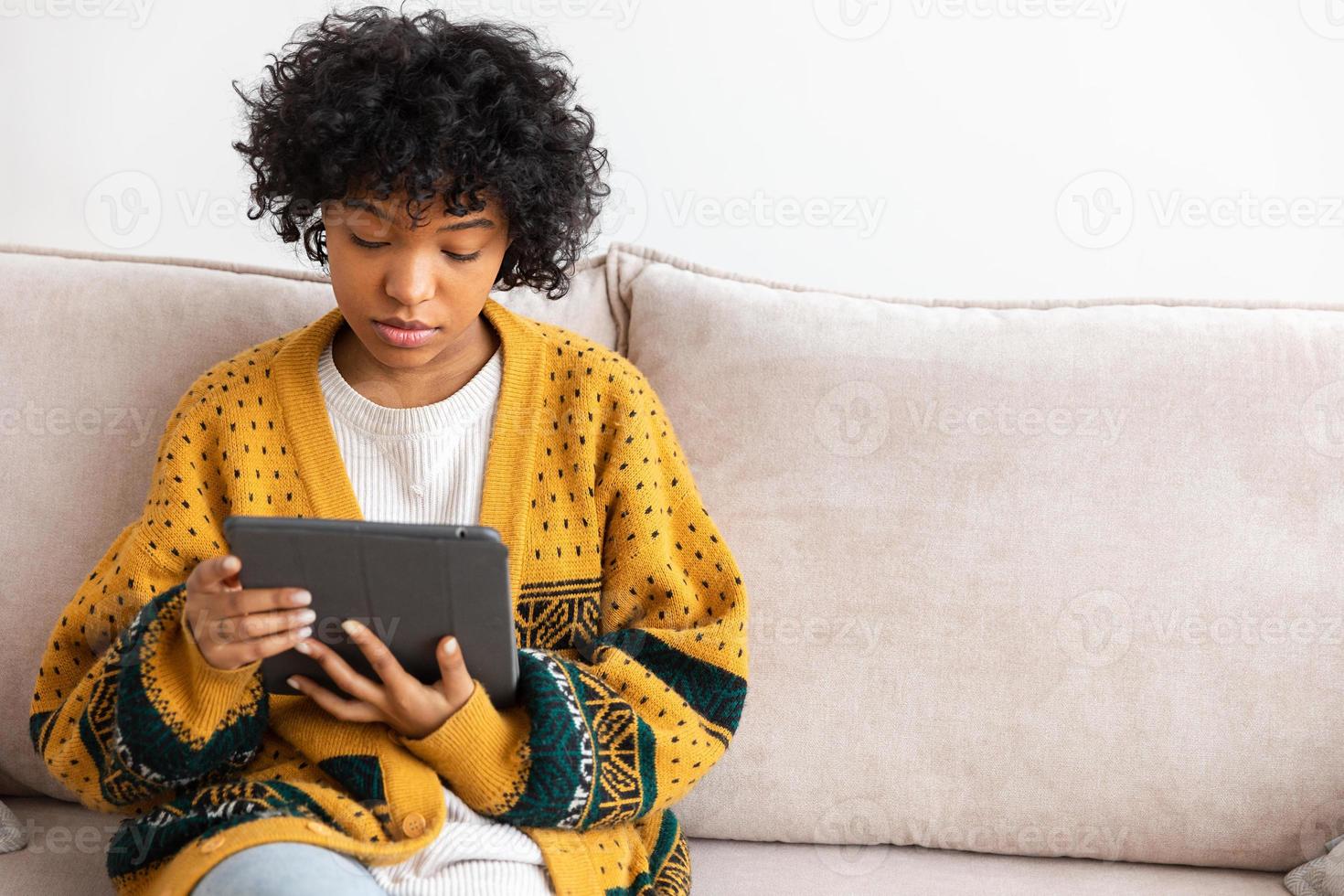 African american girl holding digital tablet touch screen typing scroll page at home. Woman with mobile tech device surfing internet using social media apps playing game. Study work shopping online. photo