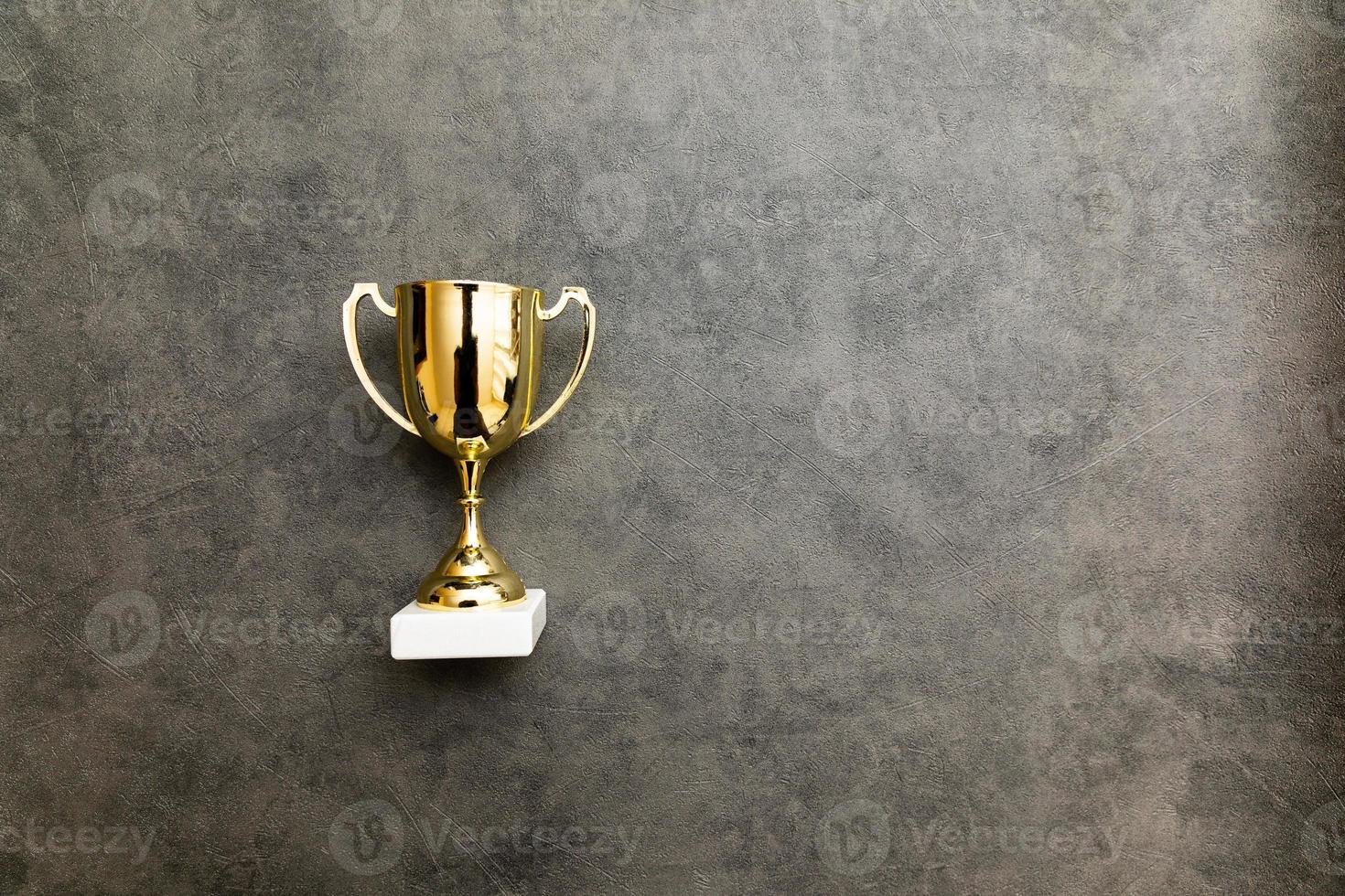Simply flat lay design winner or champion gold trophy cup on concrete stone grey background. Victory first place of competition. Winning or success concept. Top view copy space. photo
