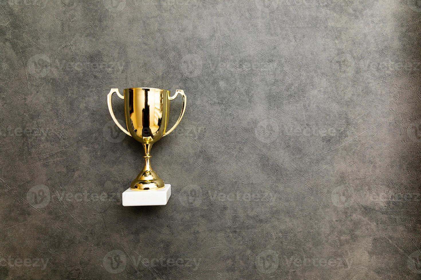 simplemente ganador de diseño plano o campeón de copa de trofeo de oro sobre fondo gris de piedra de hormigón. victoria primer lugar de la competencia. concepto ganador o de éxito. espacio de copia de la vista superior. foto