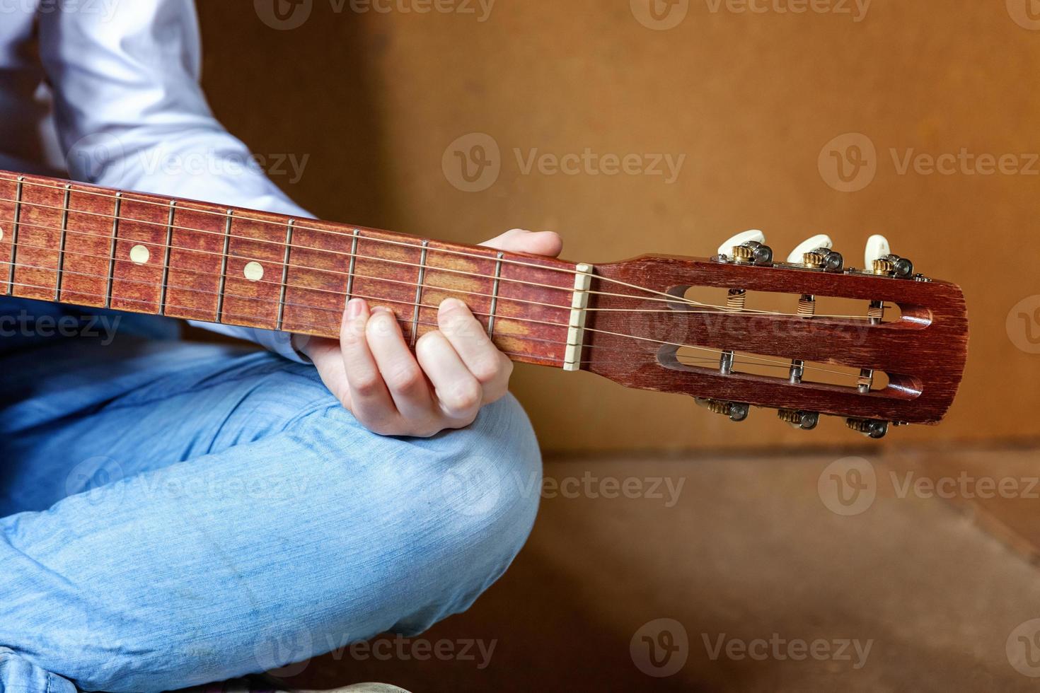 manos de una joven hipster tocando la guitarra en casa. adolescente aprendiendo a tocar canciones y escribiendo música en su habitación. hobby, estilo de vida, relajación, instrumento, ocio, concepto de educación. foto