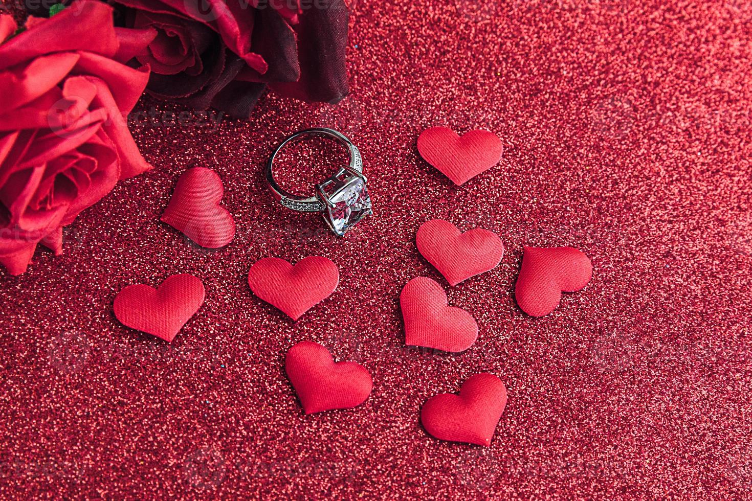 Te casarías conmigo. anillo de bodas rosas escarlatas rojas y muchos corazones rojos sobre fondo de brillo rojo. concepto de boda de propuesta de matrimonio de compromiso. S t. postal del día de san valentín. pancarta en el día de san valentín. foto