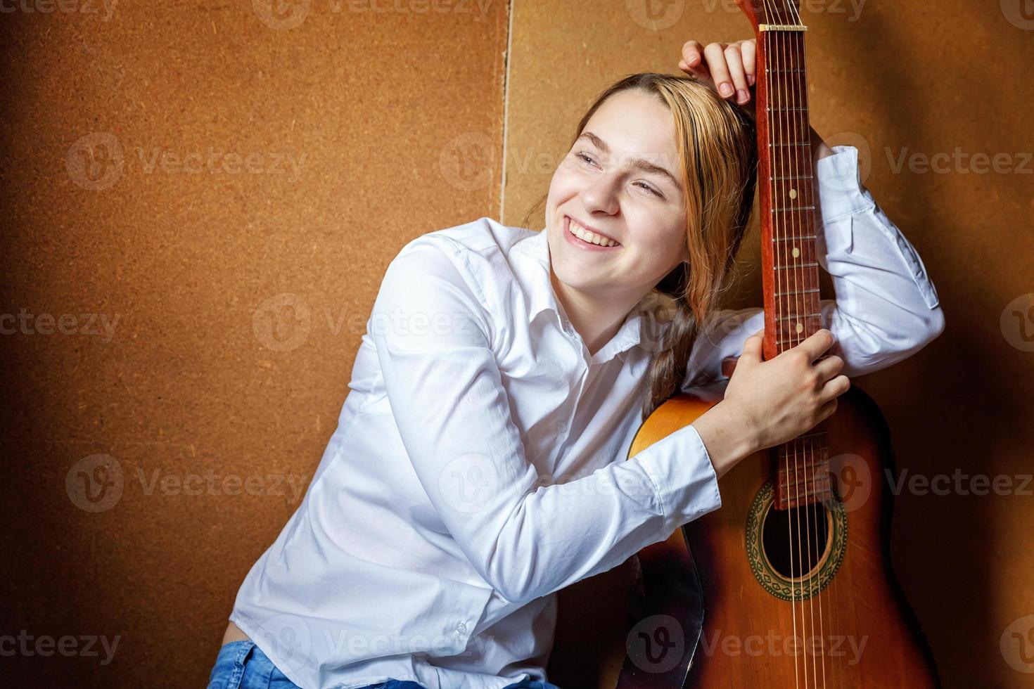 Young hipster woman sitting on floor and playing guitar at home. Teen girl learning to play song and writing music in her room. Hobby, lifestyle, relax, Instrument, leisure, education concept. photo