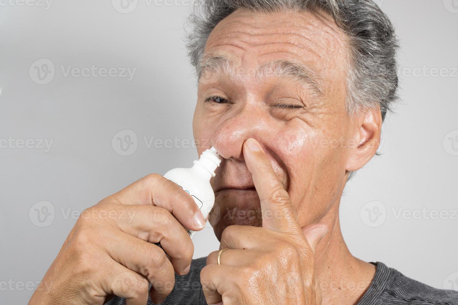 Senior man using a Nasal Spray for his dry nose photo