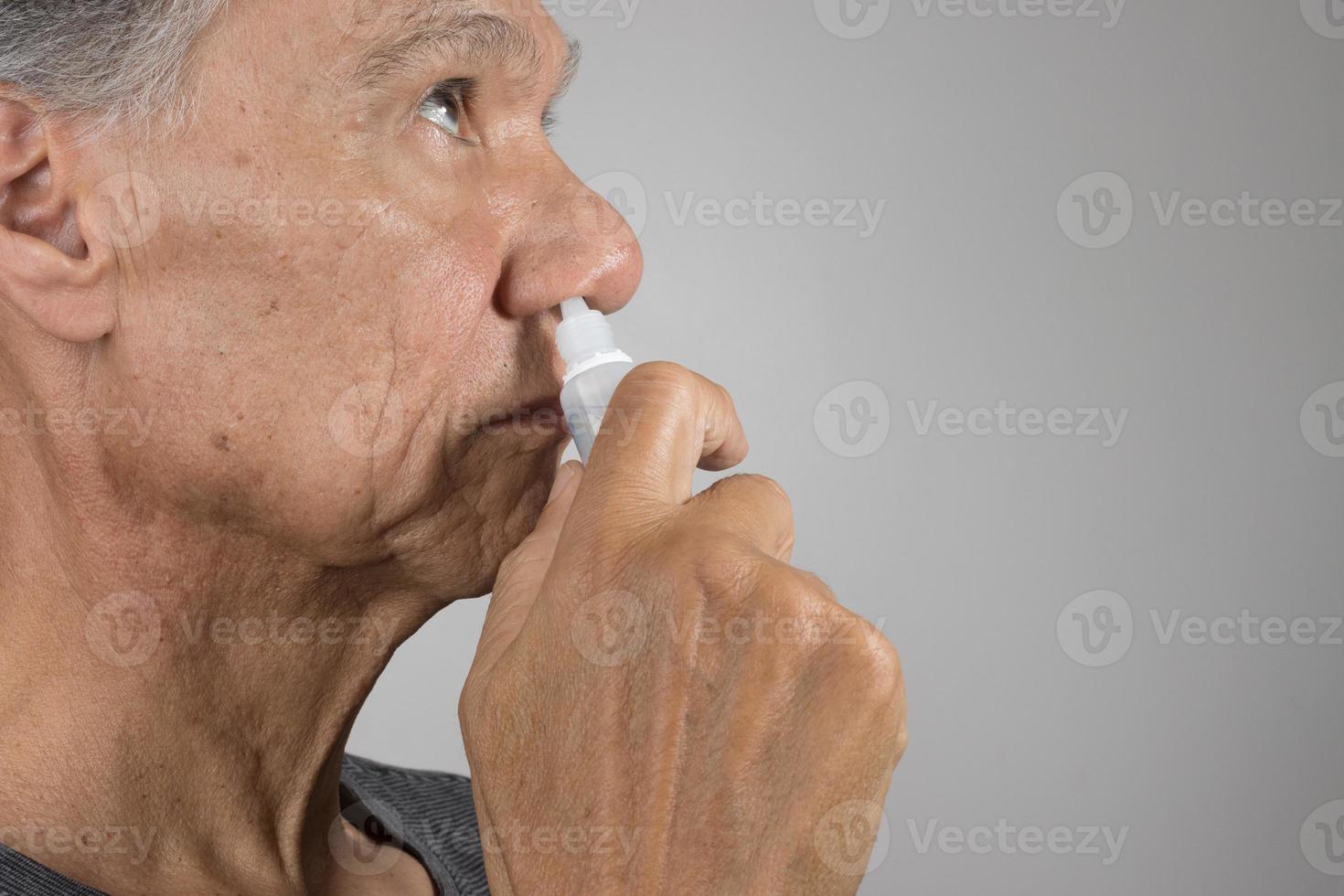 Senior man using a Nasal Spray for his dry nose photo