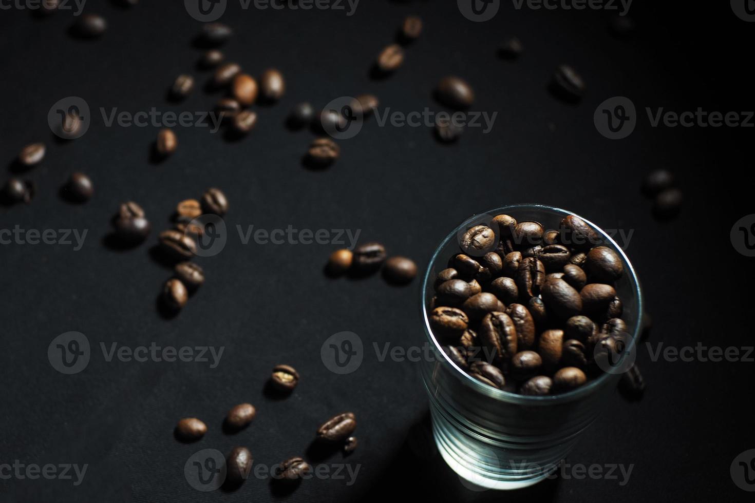 granos de café en un vaso sobre un fondo negro foto