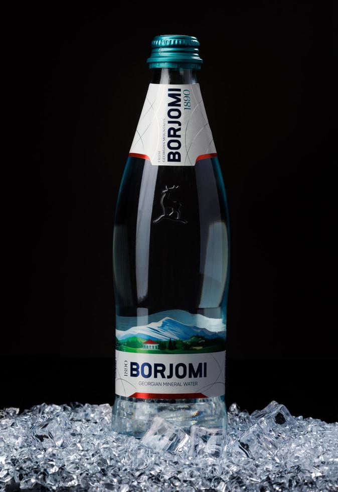 KRASNOYARSK, RUSSIA - OCTOBER 21, 2022 A bottle of Borjomi mineral water stands on a hill of crushed ice. photo
