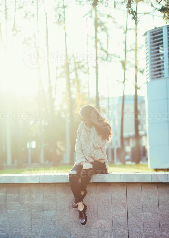 elegante mujer morena sentada en la ciudad foto