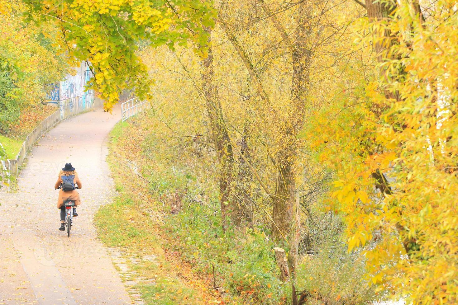 mujer montando la bicicleta en temporada de otoño. vista desde atrás foto