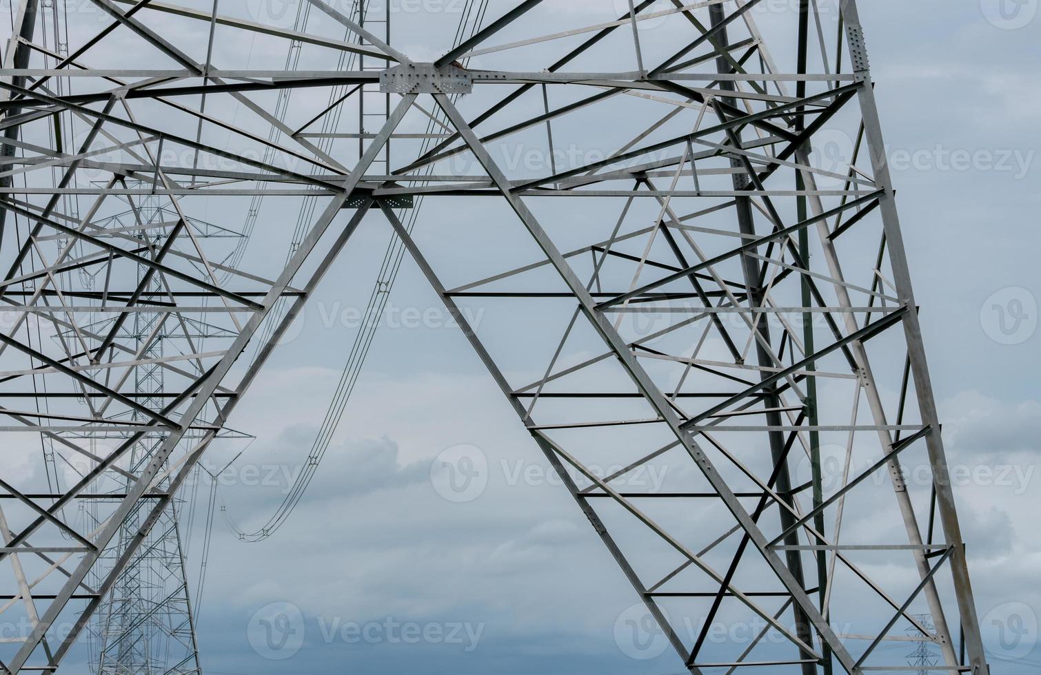 High voltage electric transmission tower. High voltage power lines against blue sky. Electricity pylon and electric power transmission lines. High Voltage tower provide power supply. Power and energy. photo