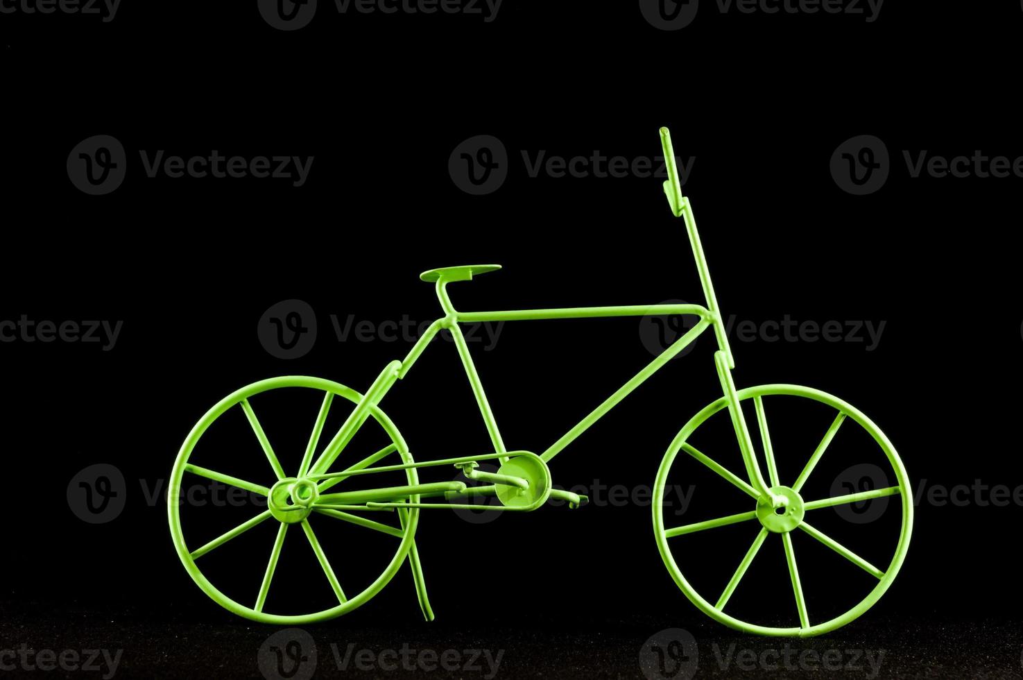 Green toy bike on black background photo