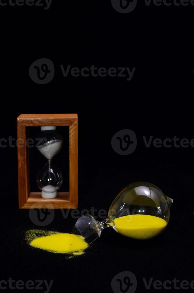 Broken hourglass on black background photo
