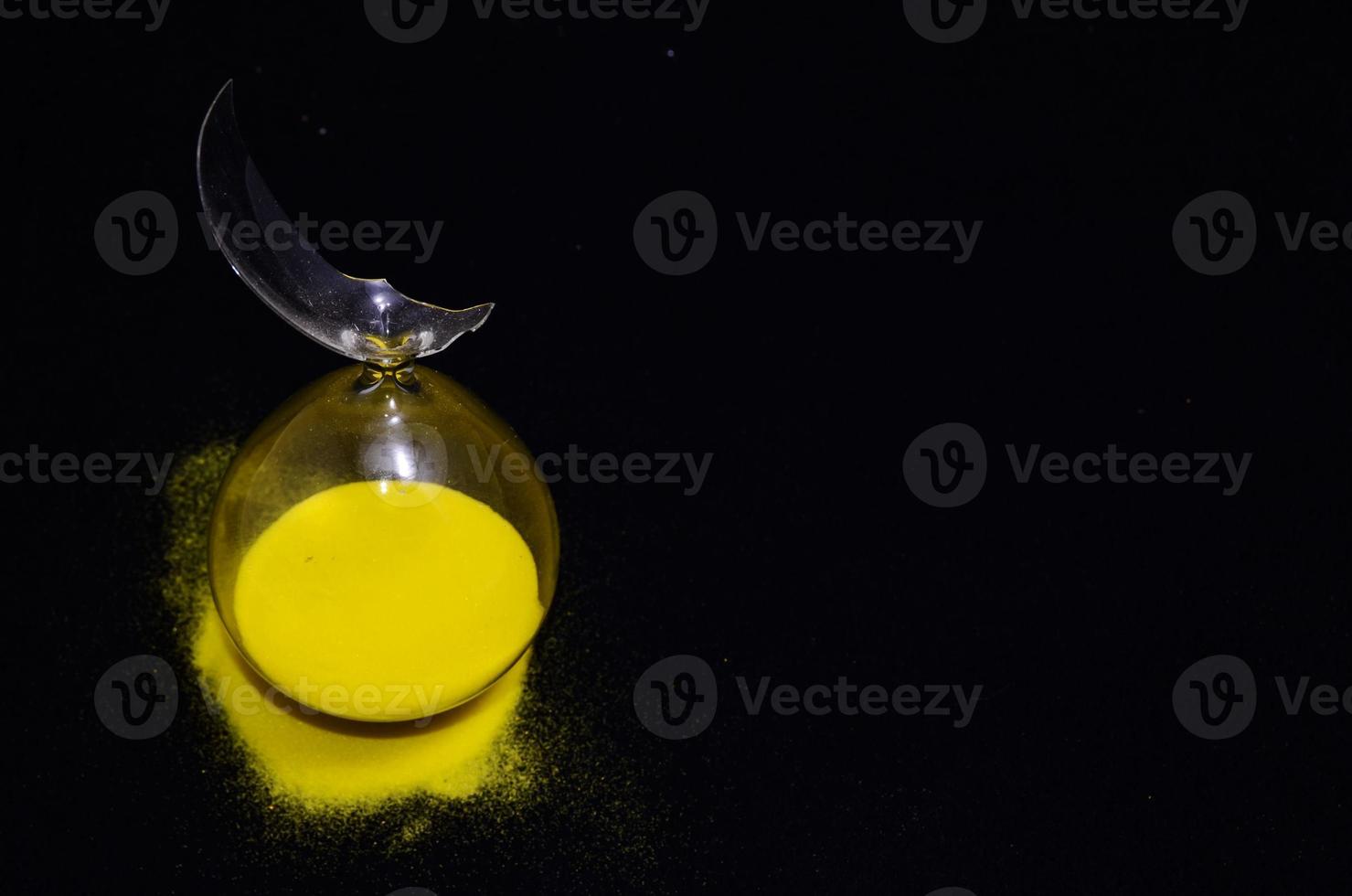 Broken hourglass on black background photo