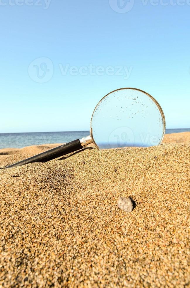 Magnifying glass in the sand photo