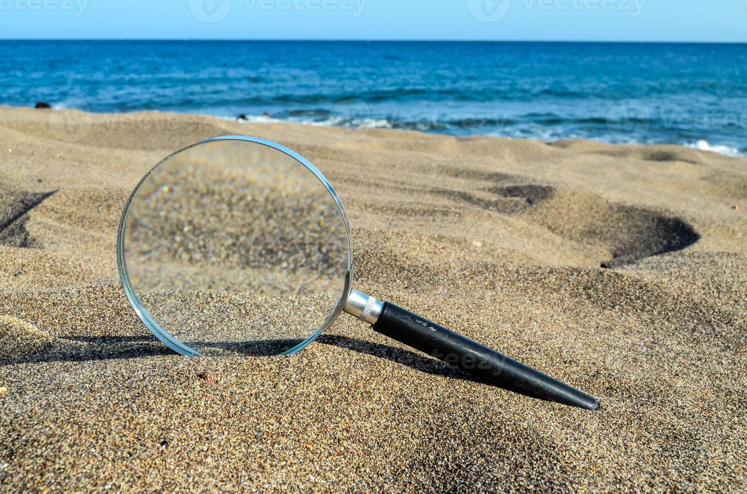 Magnifying glass in the sand photo