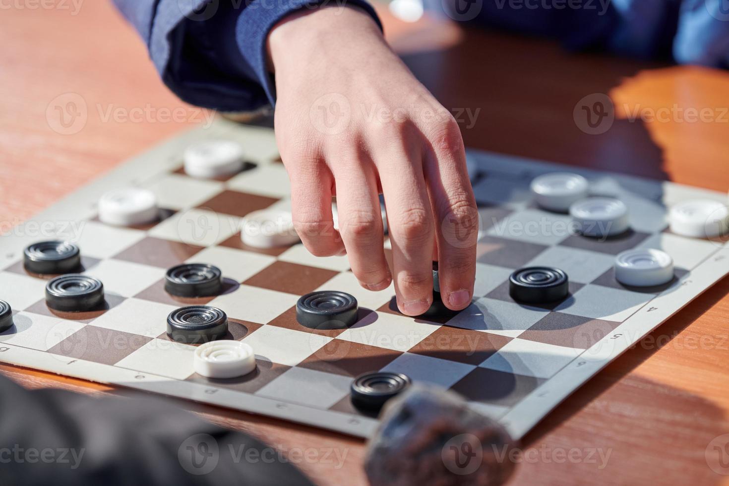 Outdoor checkers tournament on paper checkerboard on table, close up players hands photo