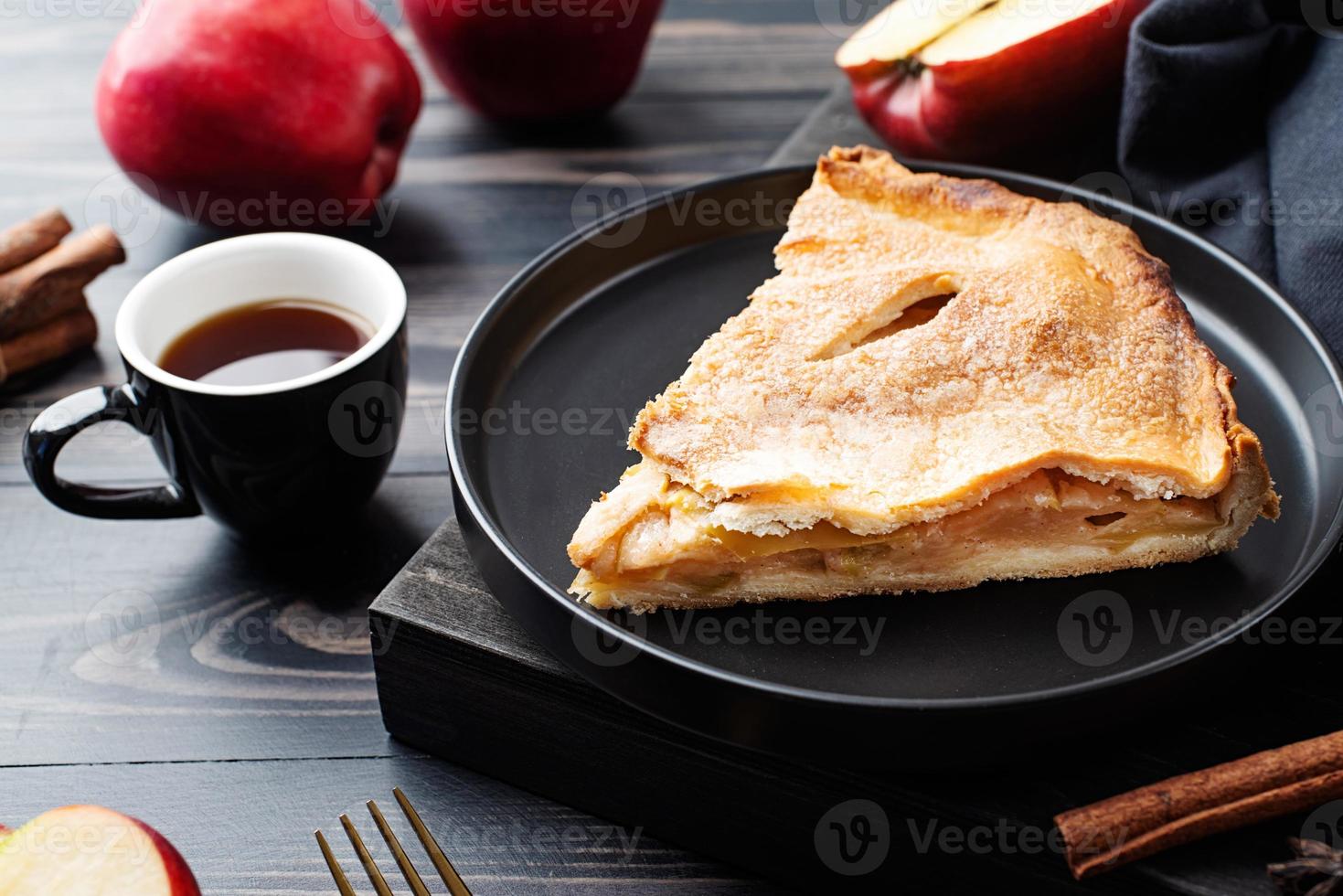 Homemade piece of apple pie with fresh red apples on black table photo