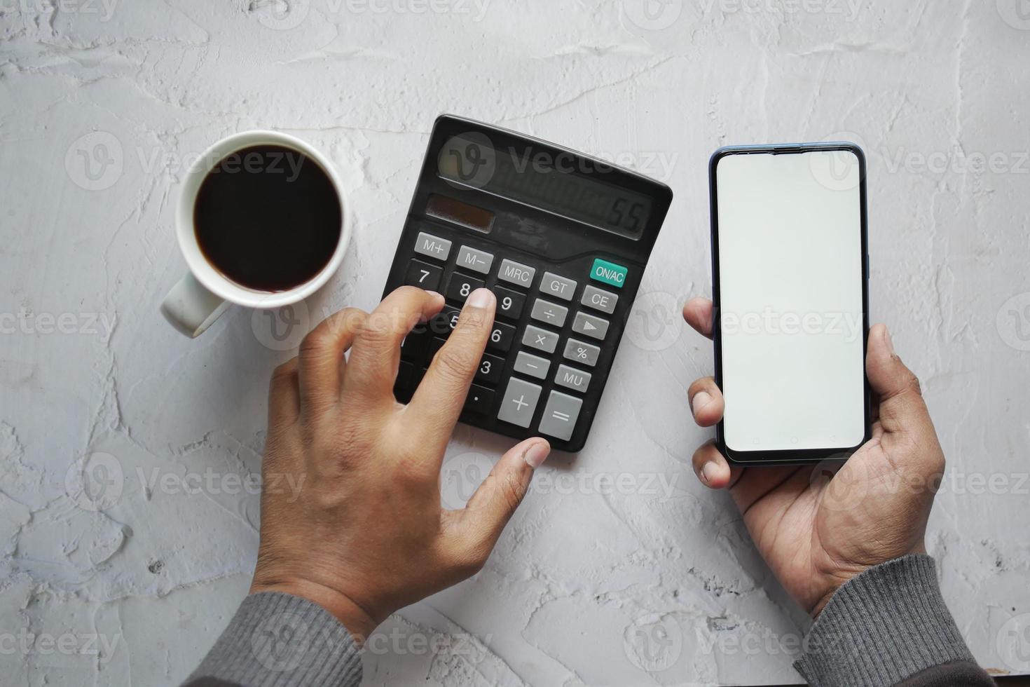 men using smart phone and calculator on table photo