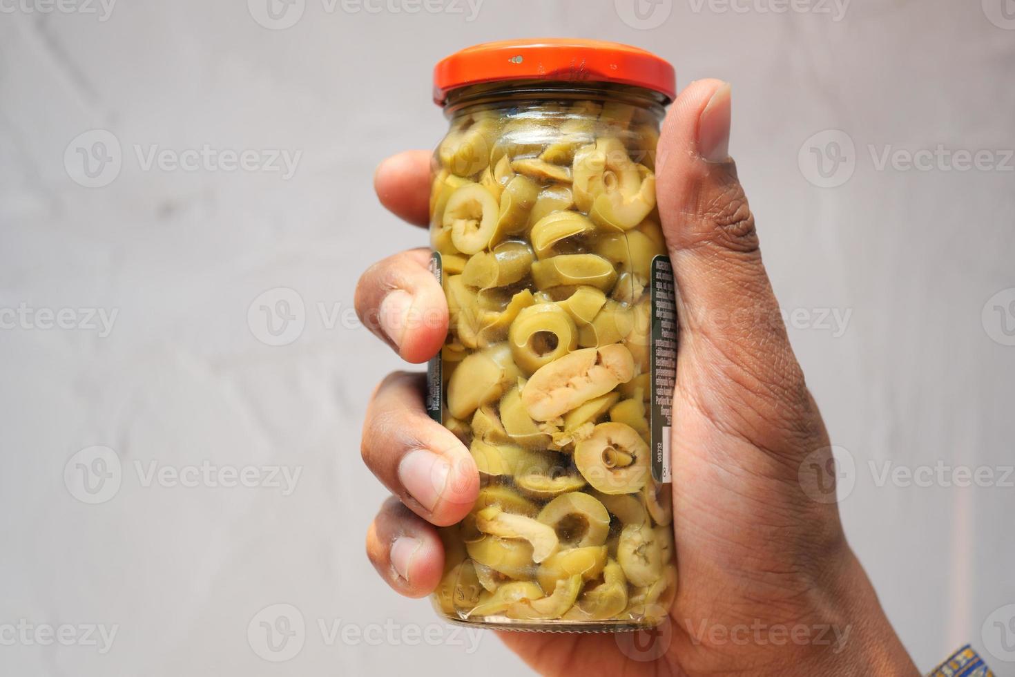 holding a jar of olive top view photo