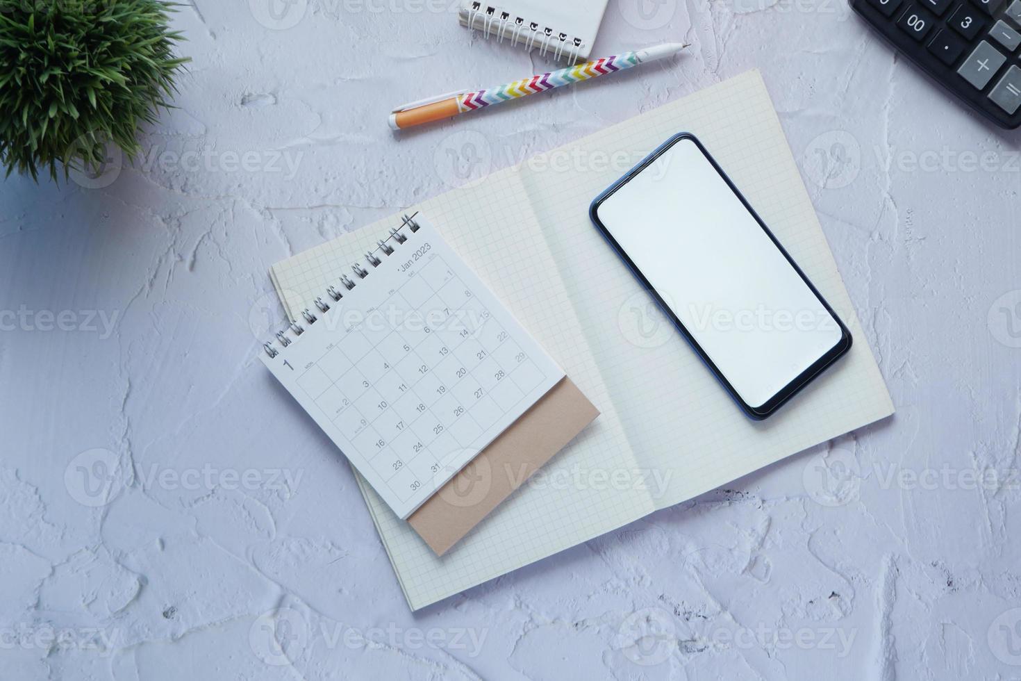 top view of calendar and smart phone with white screen on table, photo