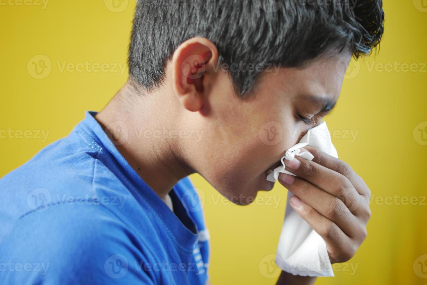 Sick boy with flu blow nose with napkin. photo