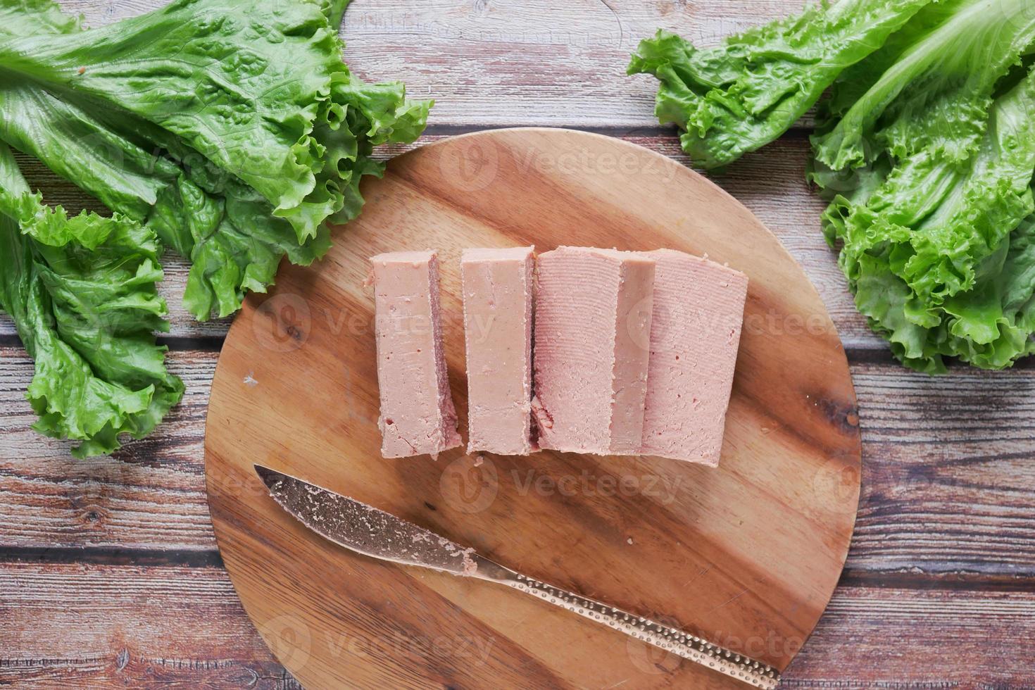 close up of cutting canned meat with a knife on table photo