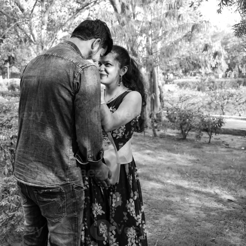 Indian couple posing for maternity baby shoot. The couple is posing in a lawn with green grass and the woman is falunting her baby bump in Lodhi Garden in New Delhi, India photo