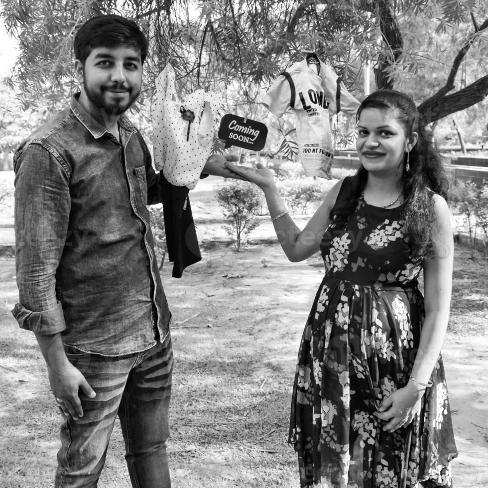 Indian couple posing for maternity baby shoot. The couple is posing in a lawn with green grass and the woman is falunting her baby bump in Lodhi Garden in New Delhi, India photo
