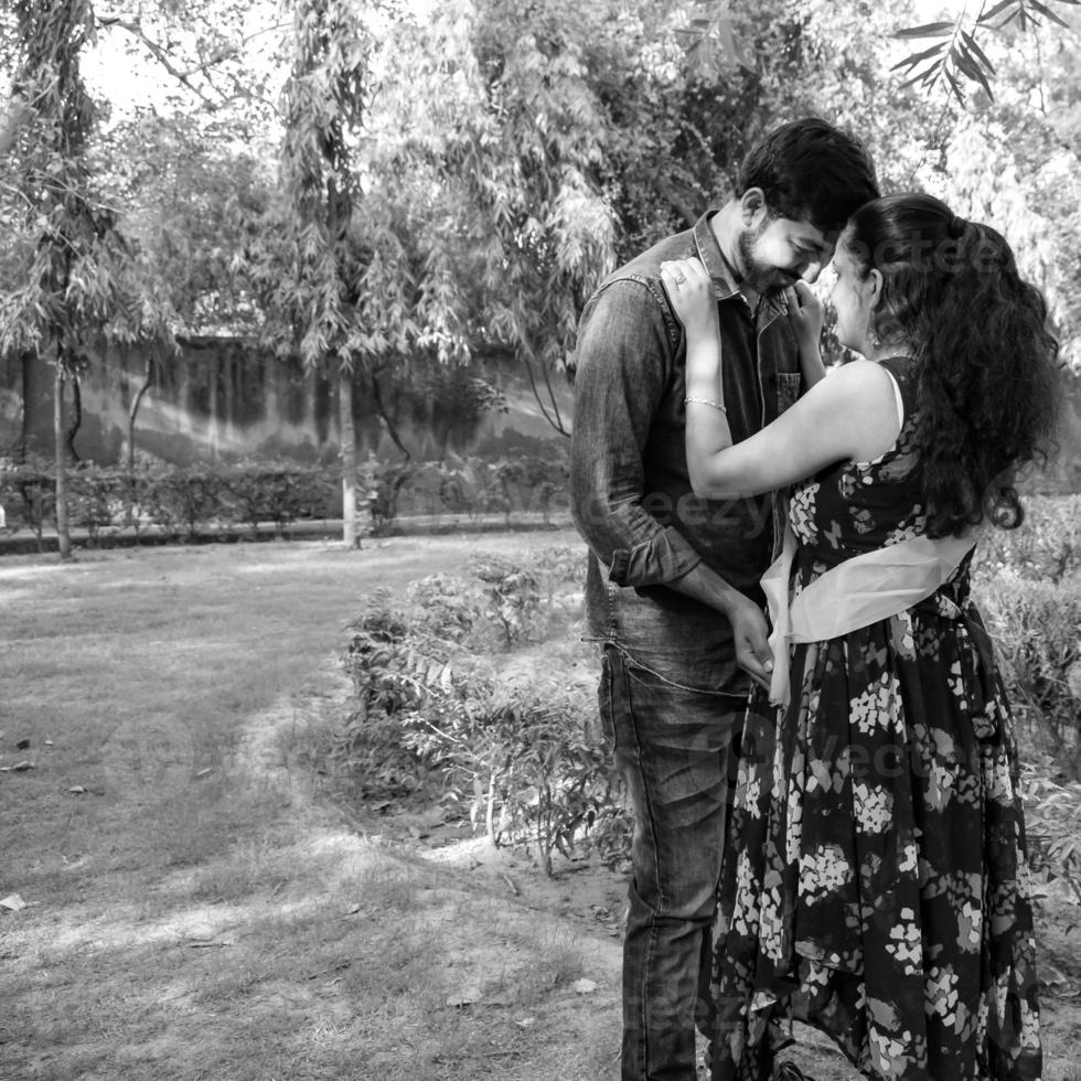 Indian couple posing for maternity baby shoot. The couple is posing in a lawn with green grass and the woman is falunting her baby bump in Lodhi Garden in New Delhi, India photo