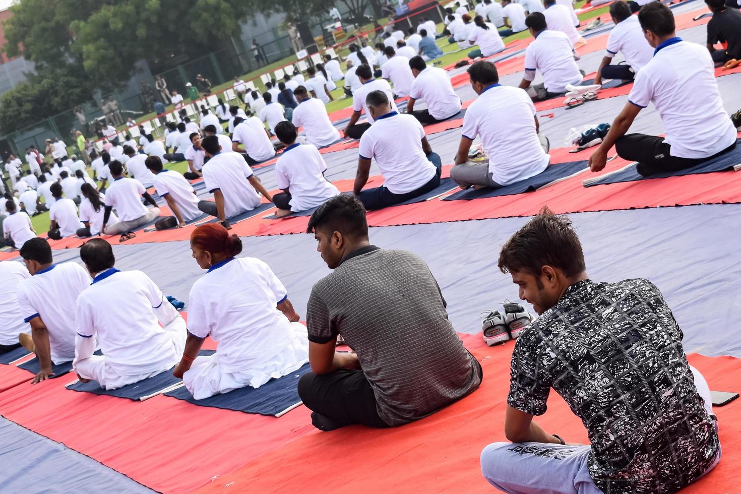New Delhi, India, June 21 2022 - Group Yoga exercise session for people at Yamuna Sports Complex in Delhi on International Yoga Day, Big group of adults attending yoga class in cricket stadium photo